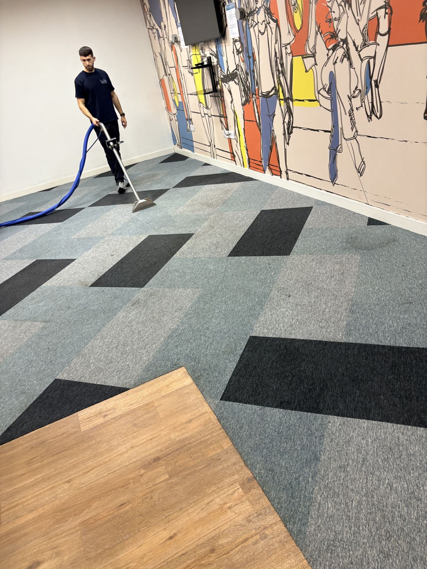 Easy Clean technician carpet cleaning with a hot water extraction wand in a patterned carpet tile office