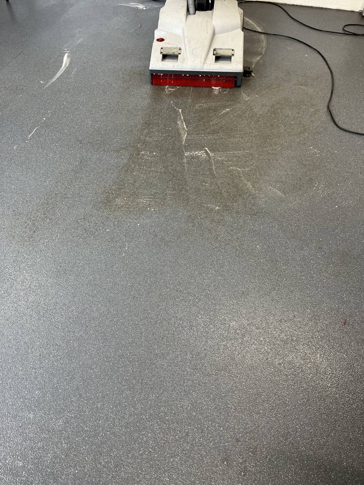 Grey resin floor with a clean, even stripe left behind by the scrubber dryer